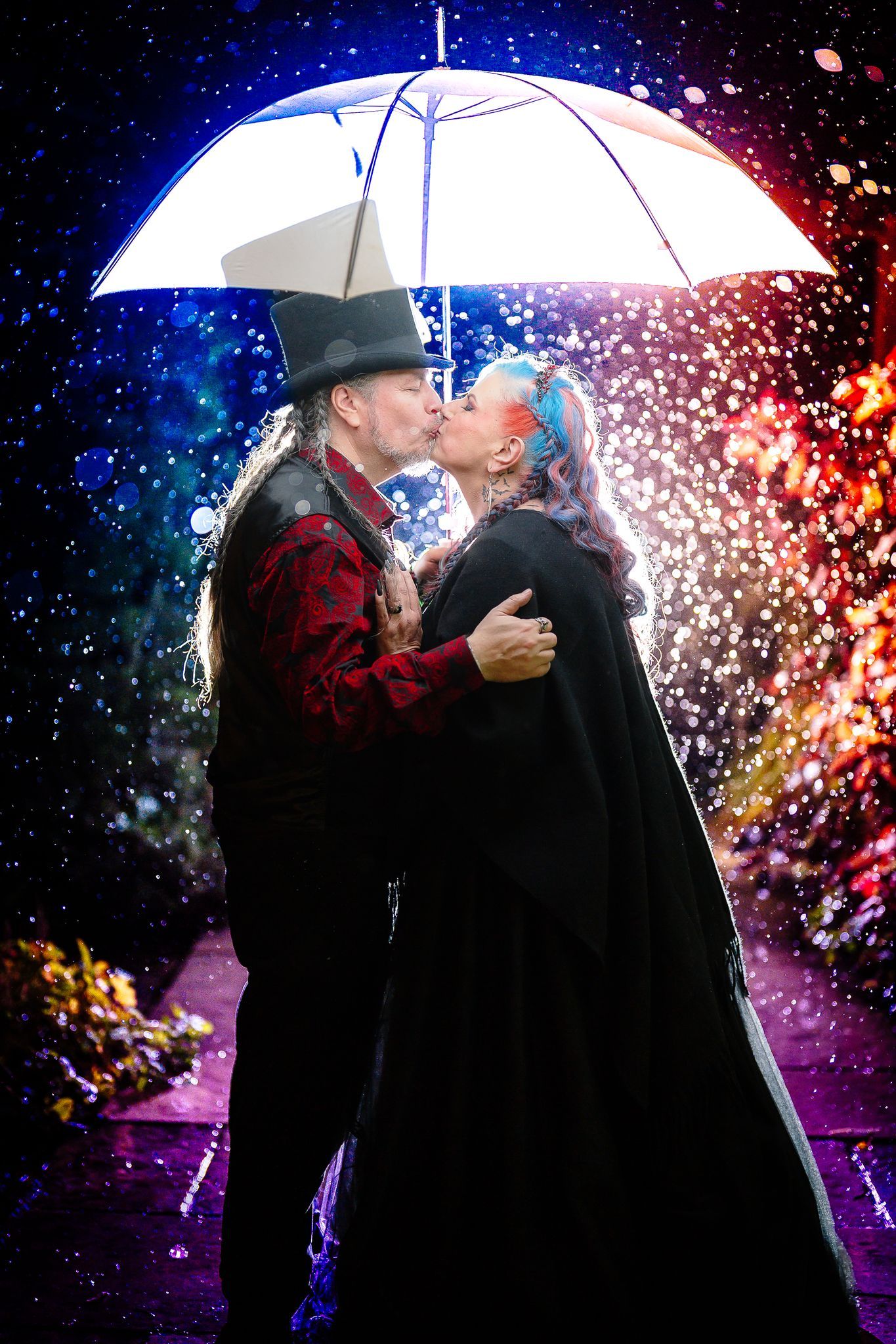 Bride and groom kissing under a white umbrella lit through falling water in a creative night wedding portrait in Northumberland