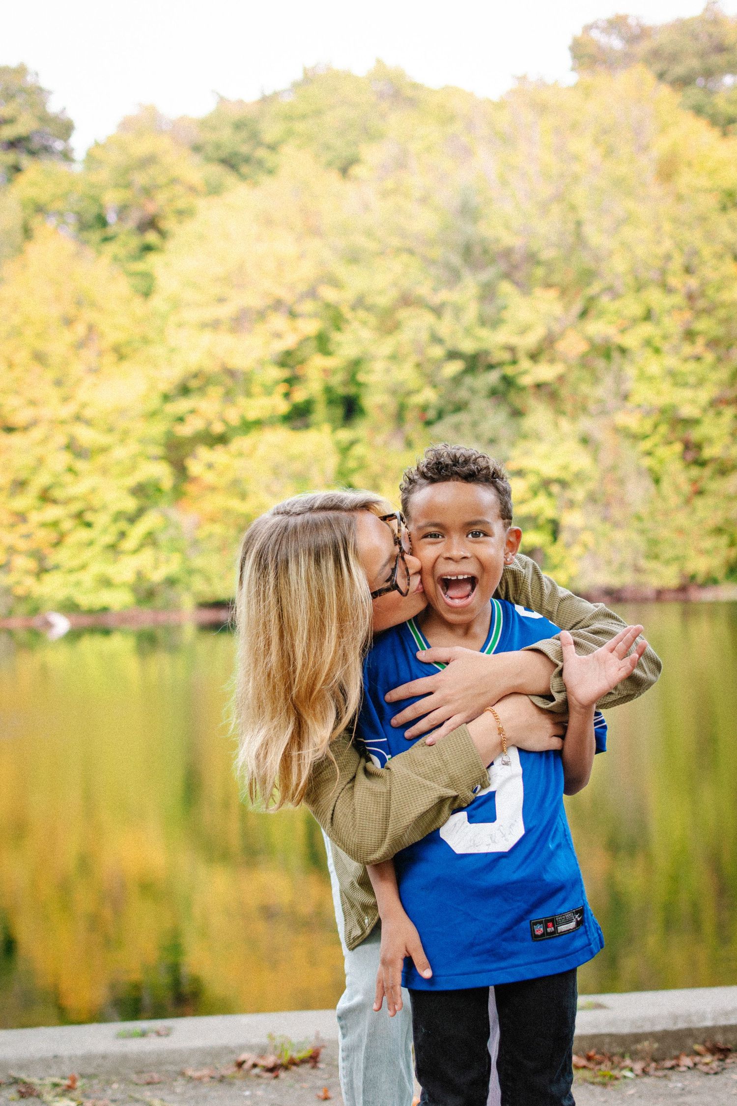 Mother lifting her smiling son during an autumn family photography session in Kent