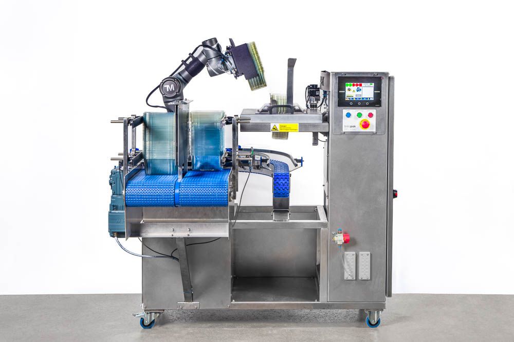 Machinery photography of stainless steel industrial food packaging machine with blue conveyor belt and control panel on white background.