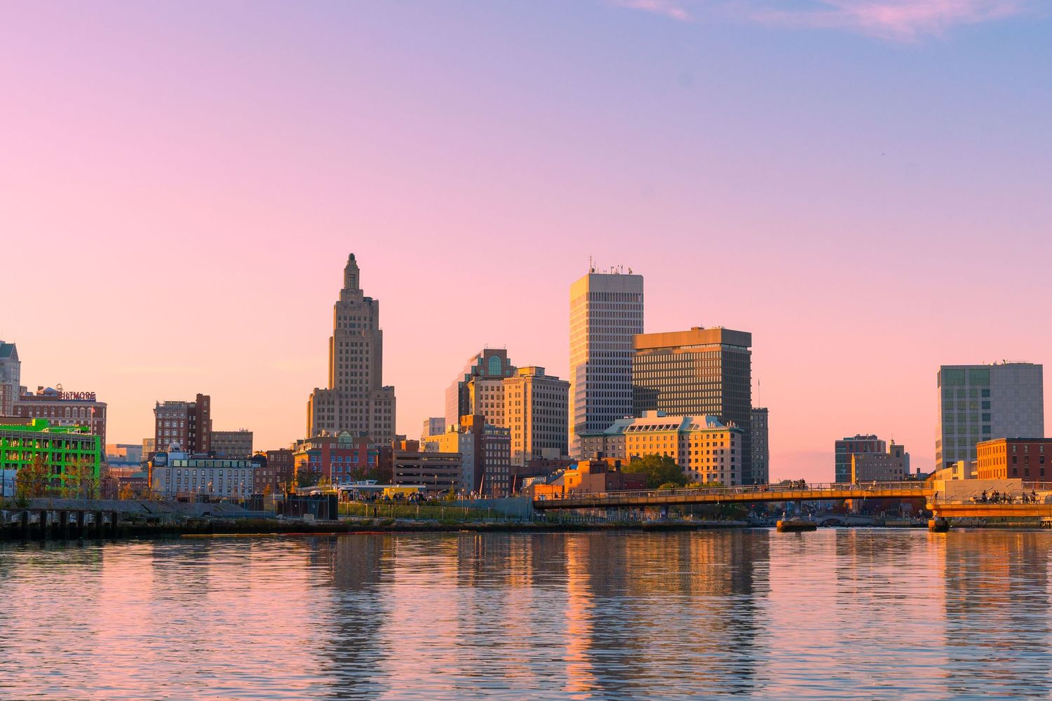 Providence Rhode Island skyline reflecting on the river at sunset with pink and purple hues in the sky.