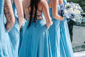 Bridesmaids in matching light blue floor-length gowns holding white and blue floral bouquets.