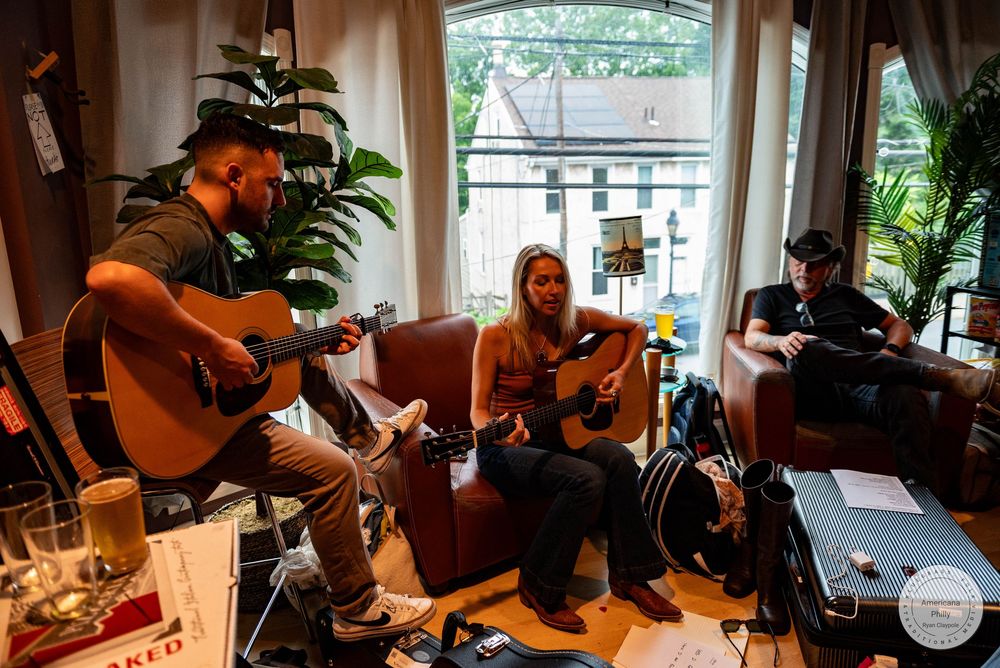 Three musicians playing acoustic guitars in a cozy living room during an informal jam session.