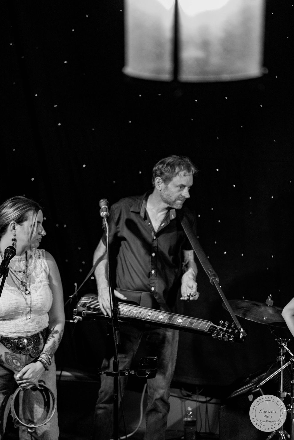 Black and white photo of a male guitarist and female vocalist performing on stage at a live music event.