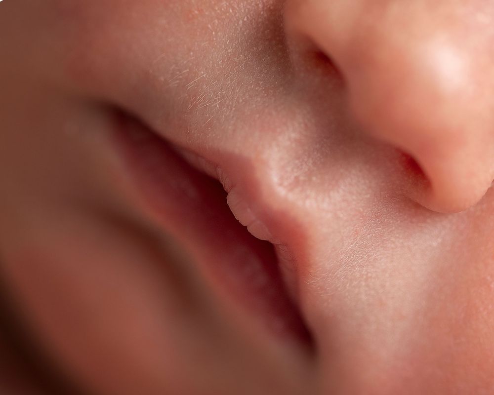 Close-up macro photo of a newborn baby's nose and lips, showcasing delicate soft skin texture.