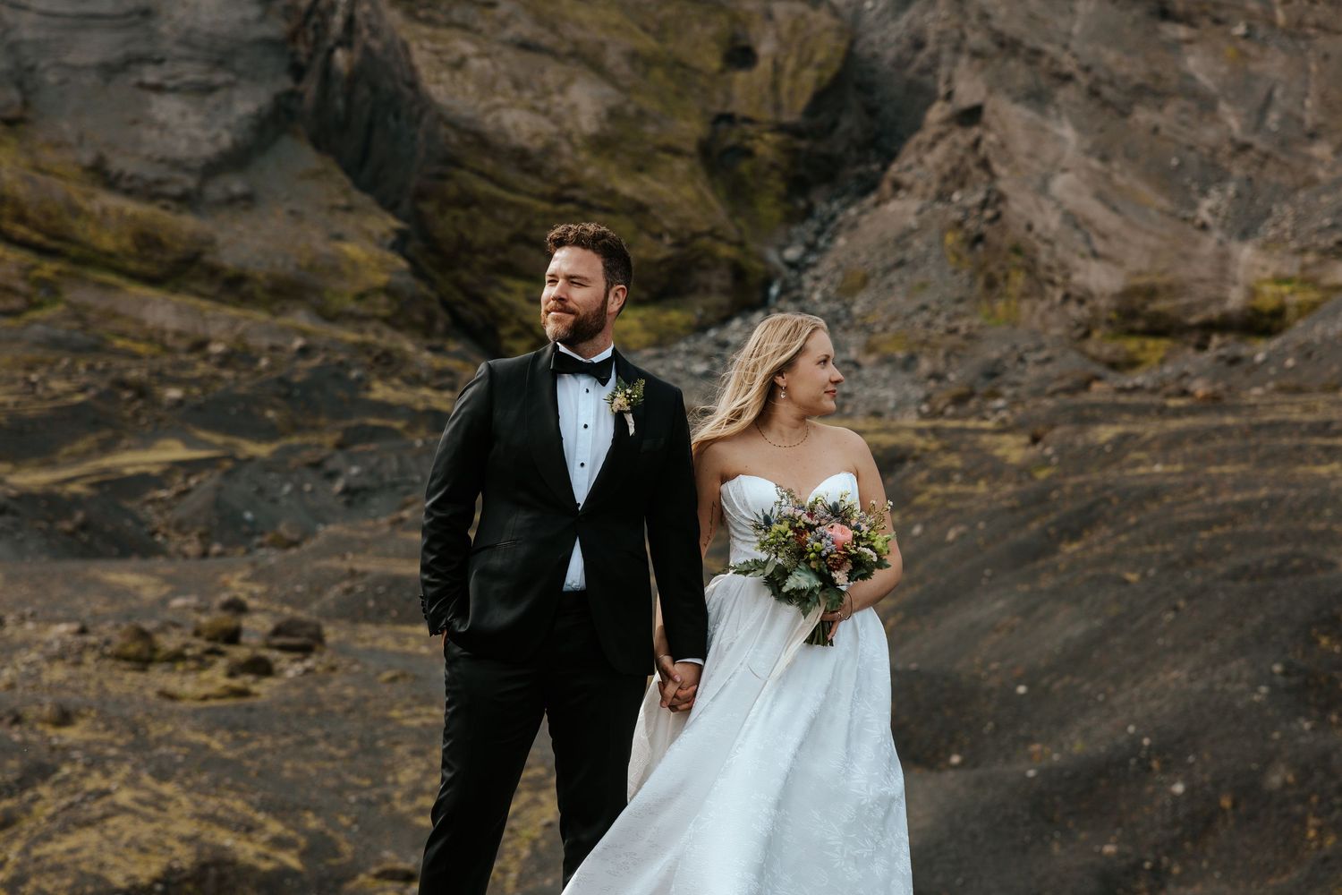 eloping couple standing side by side, holding hands and looking opposite directions in Thórsmörk, Iceland