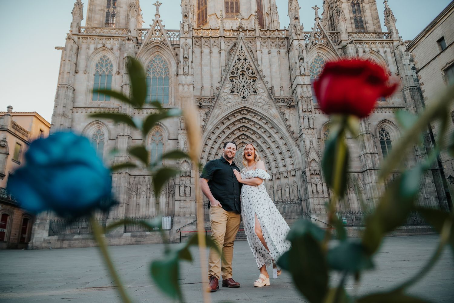 A romantic babymoon portrait of a couple embracing in a narrow, sunlit cobblestone street in the Old City of Barcelona.