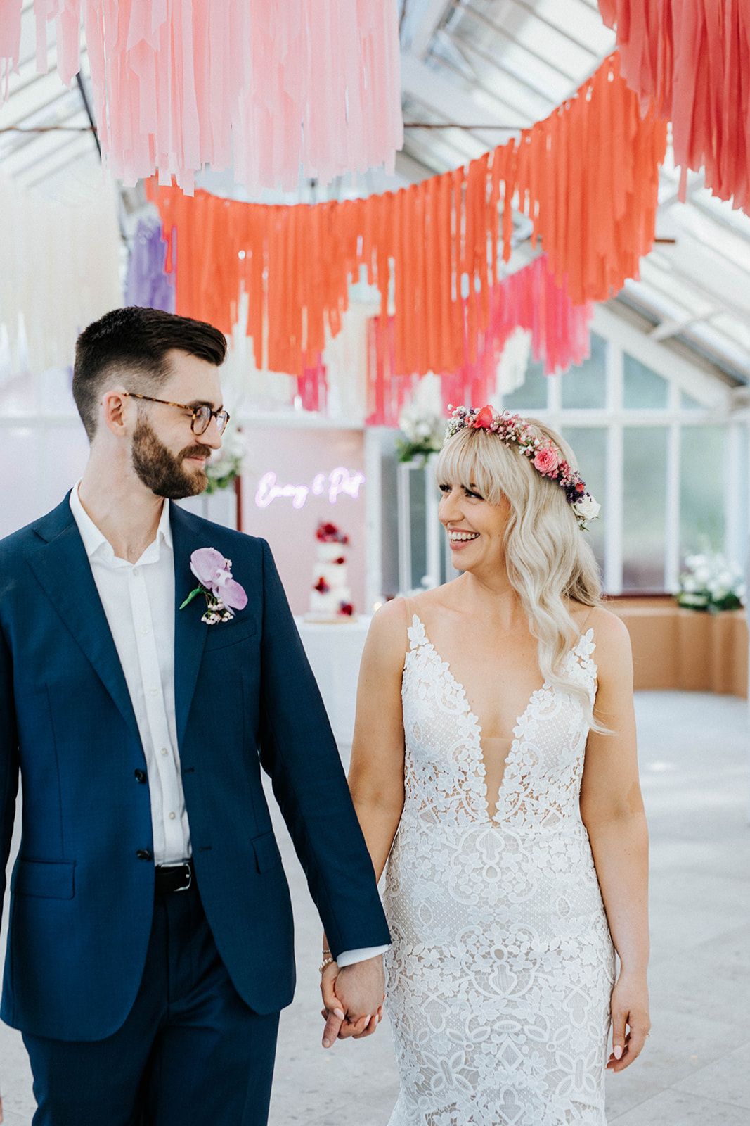 Bride and groom stand on a tree-lined path at an outdoor wedding venue surrounded by lush greenery.