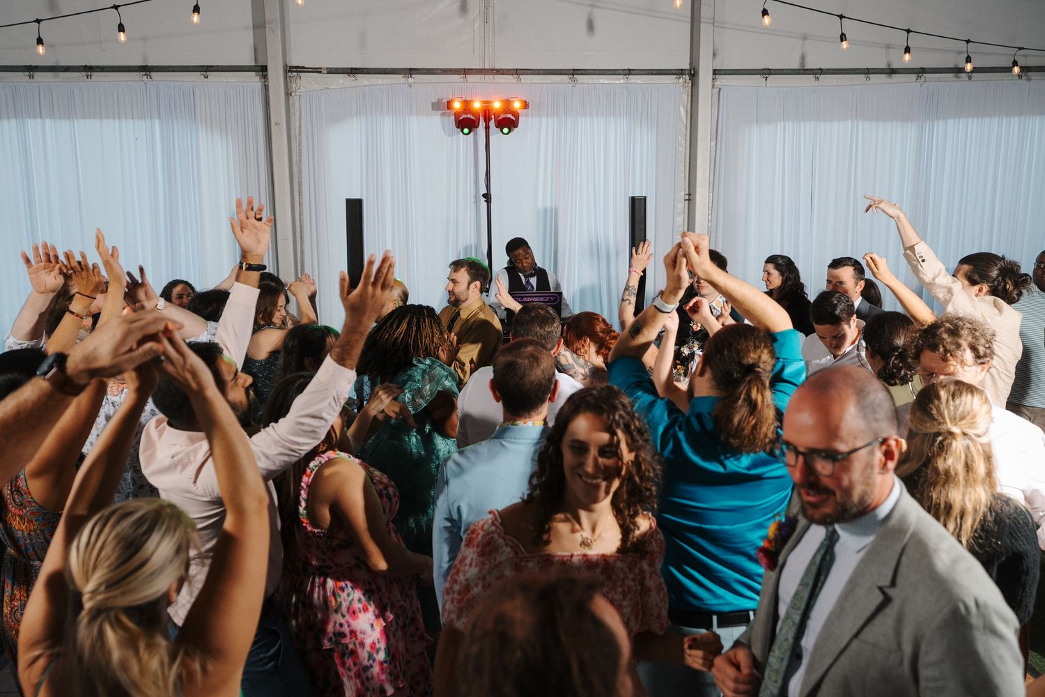 Guests dancing with hands raised at a lively wedding reception for Mackie and Briana at Winter Lodge Events Venue near Mount Rainier.