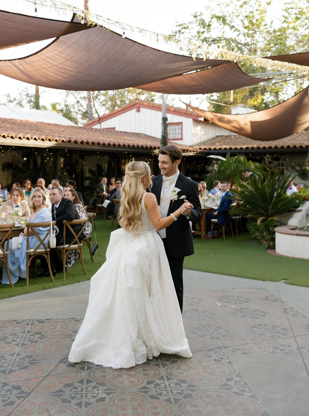 Bride and groom sharing first dance at outdoor wedding reception under shade canopy.