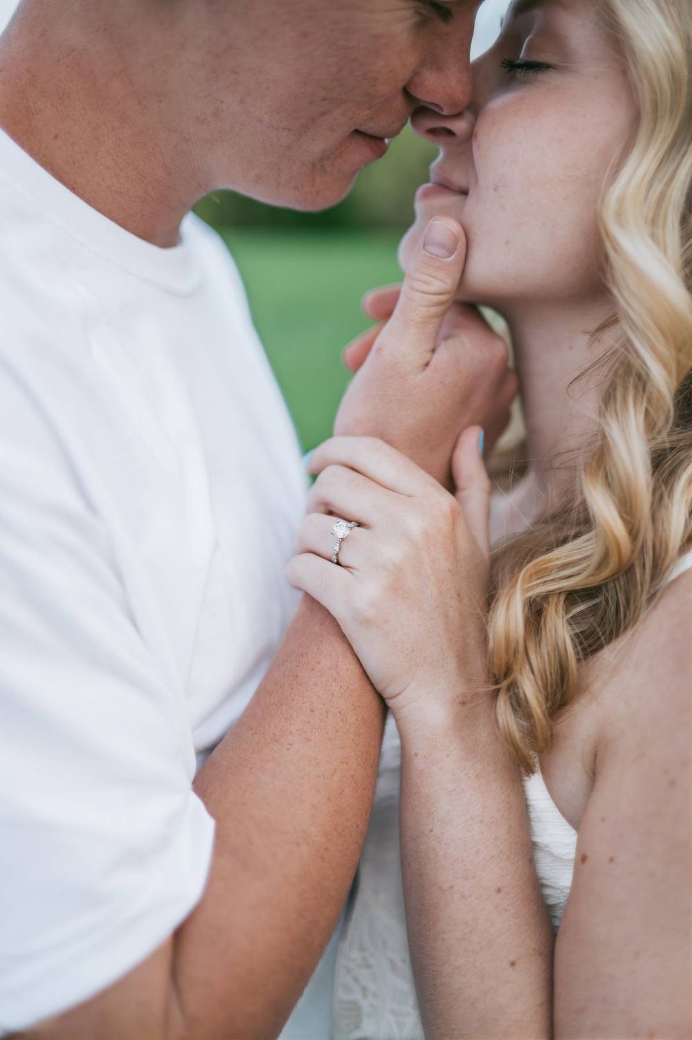 Close-up of couple sharing a tender kiss, woman displaying diamond engagement ring while embracing, engagement photographer Lexington NC