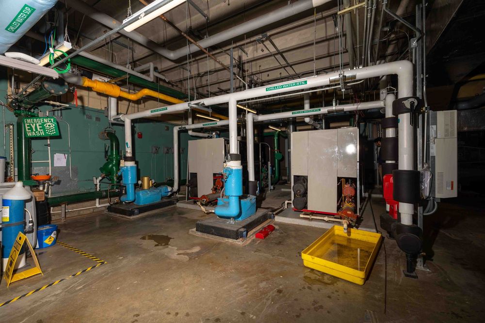 Industrial mechanical room with boilers, pumps, and piping systems in a commercial building utility space.