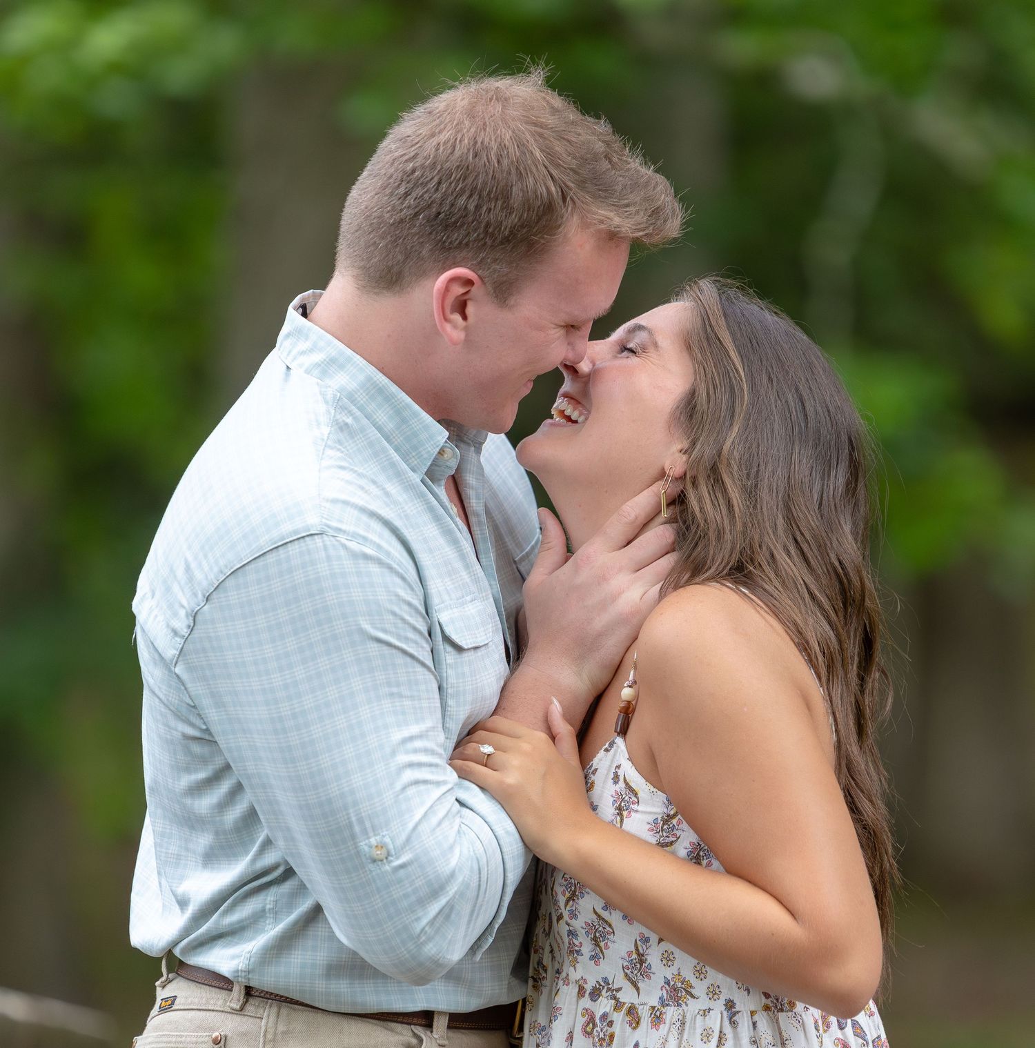 Engagement Photo Calhoun, GA A woman and teenage girl sit smiling beside a young boy against a rustic brick wall outdoors.