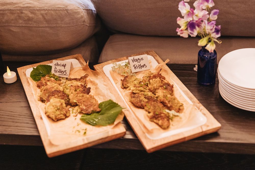 Two wooden serving boards with crispy fried appetizers and fresh basil leaves displayed on a table at a catered event.