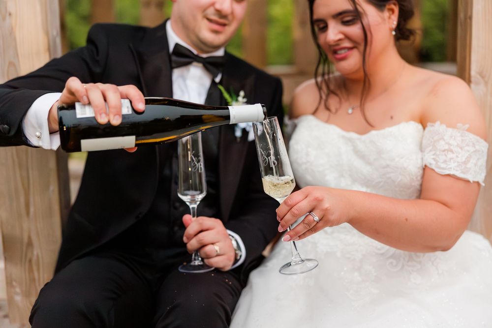 Bride and groom pouring champagne into flutes during wedding reception celebration.