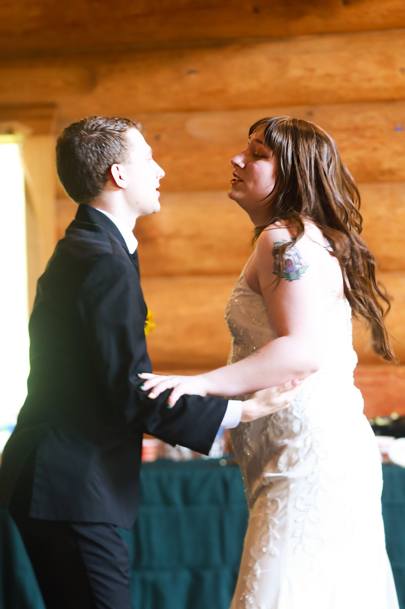 Bride and groom share their first dance in a rustic log cabin wedding venue.
