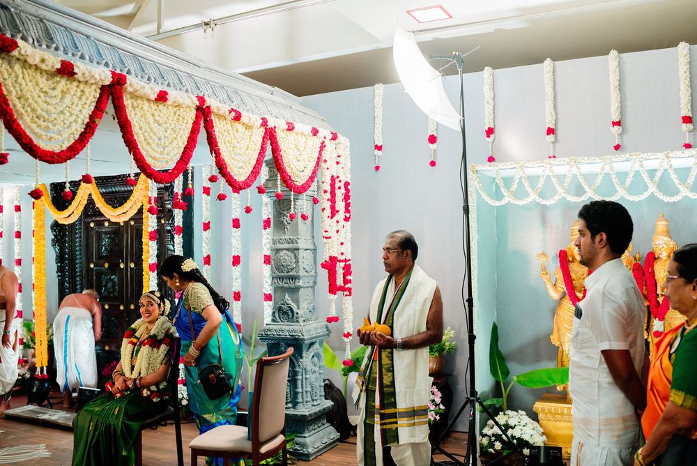 Hindu wedding ceremony with colorful floral decorations and garlands at an indoor temple altar.