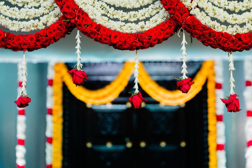 Decorative red white and yellow flower garlands adorning a black doorway at an Indian wedding venue.