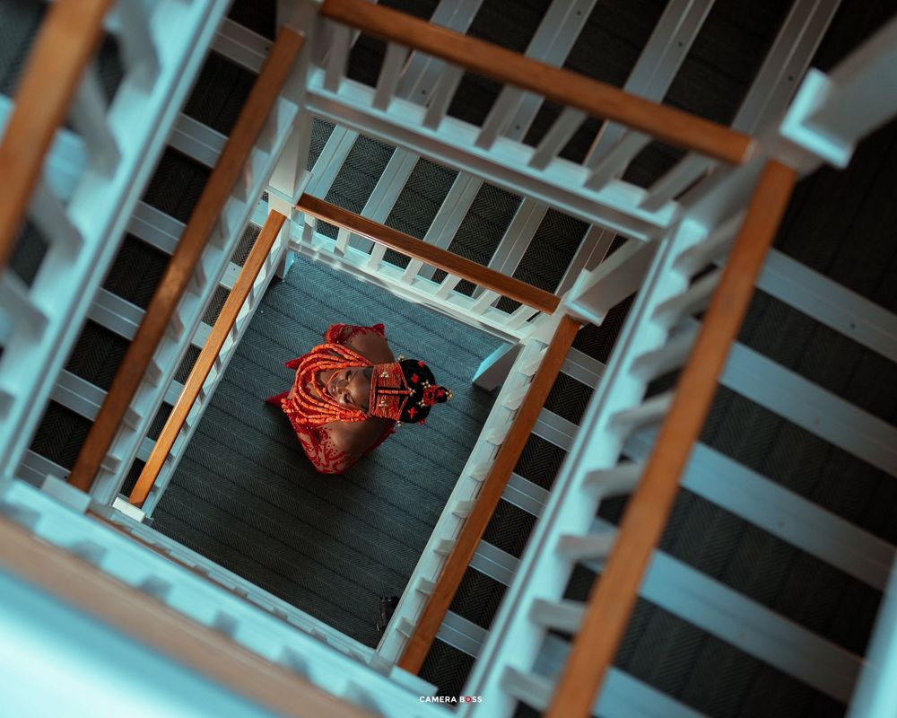 Aerial view of a spiral staircase with a person in a red outfit standing at the bottom center.