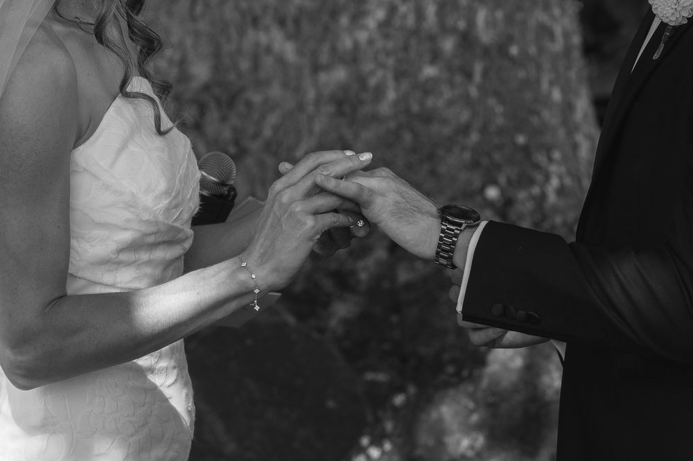 Black and white photo of a couple exchanging wedding rings during a marriage ceremony.