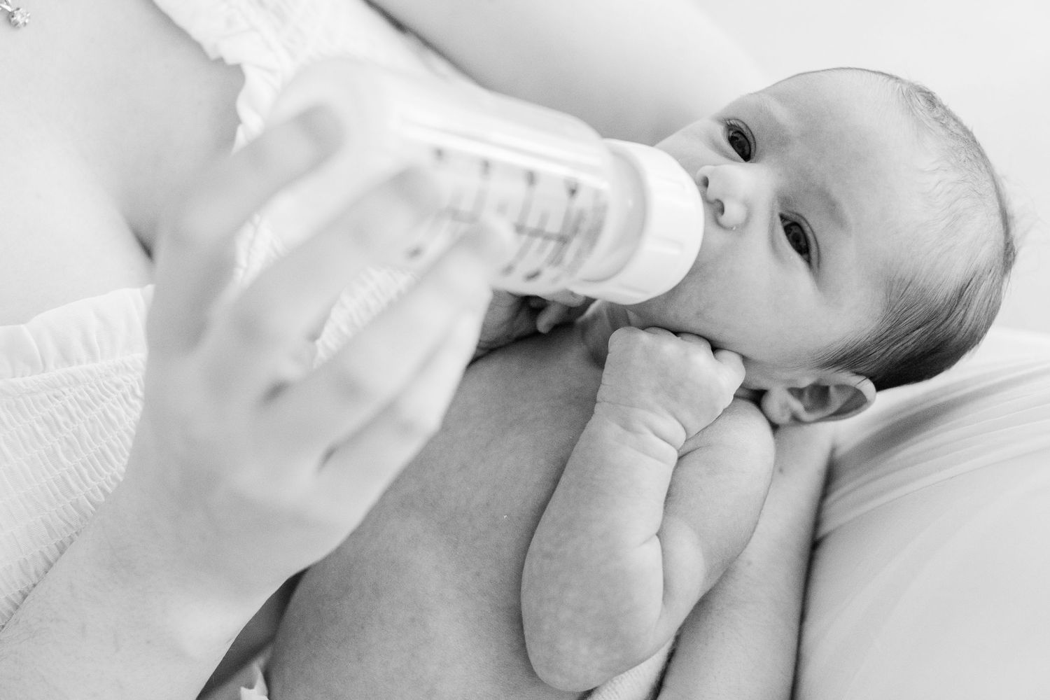Black-and-white portrait of a newborn drinking a bottle. In-home lifestyle newborn session in Guaynabo, Puerto Rico.