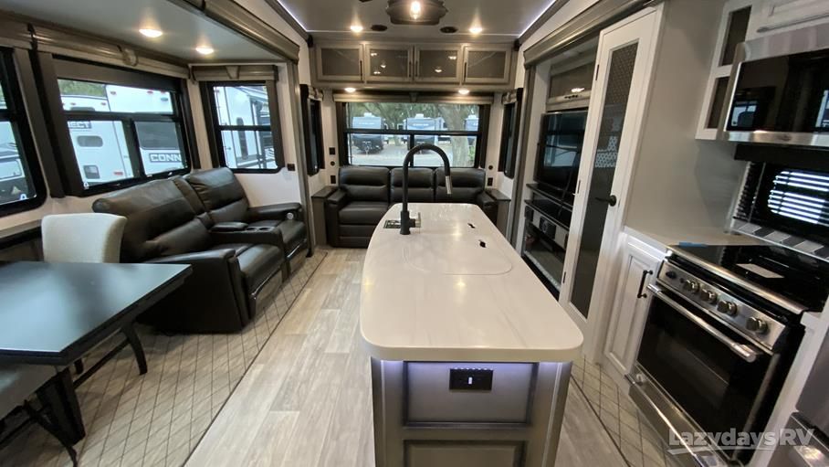 Spacious RV interior featuring a white kitchen island, modern appliances, and open living area.