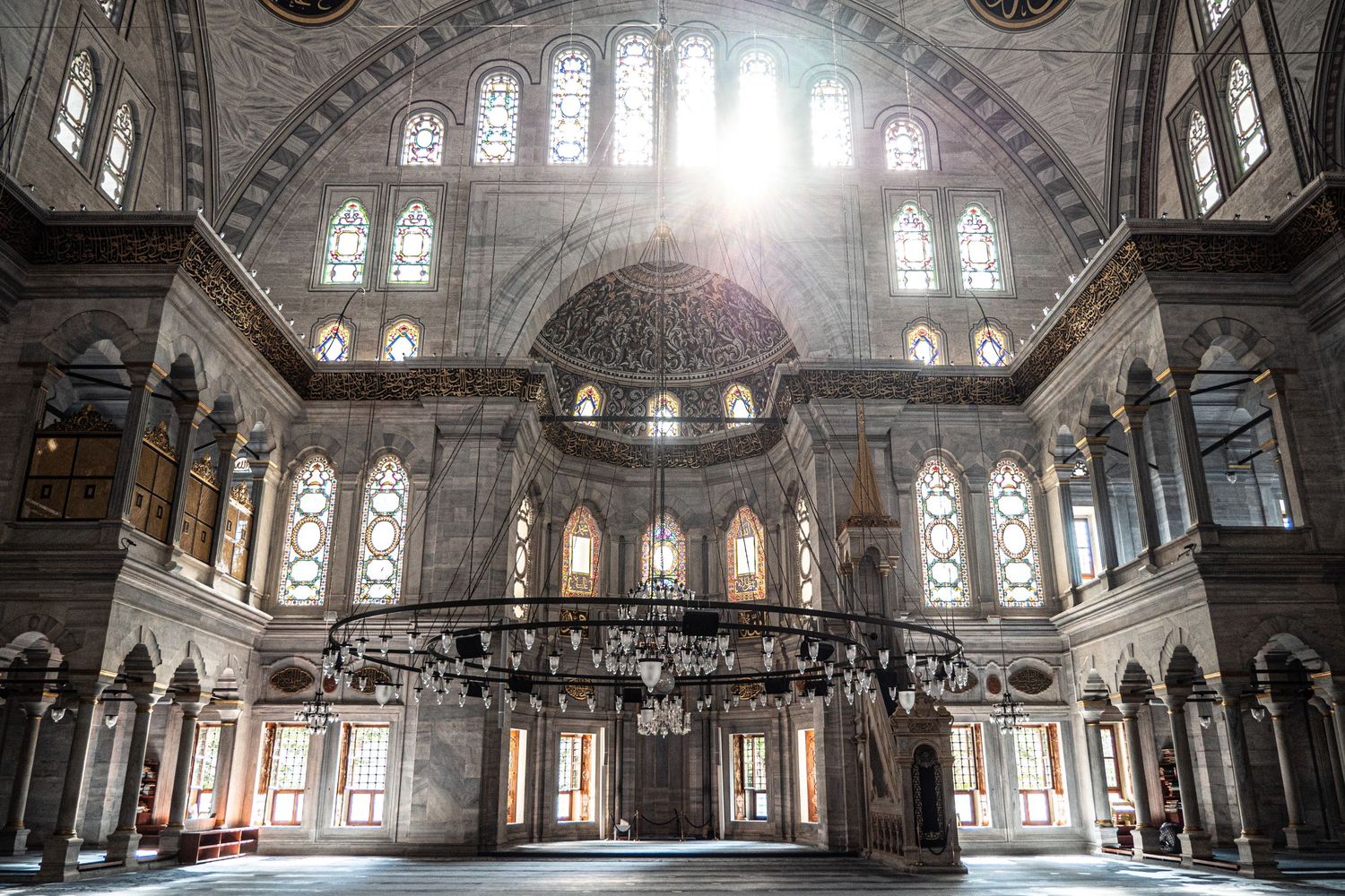 Inside beautiful sunlit mosque with white interior and rainbow windows.