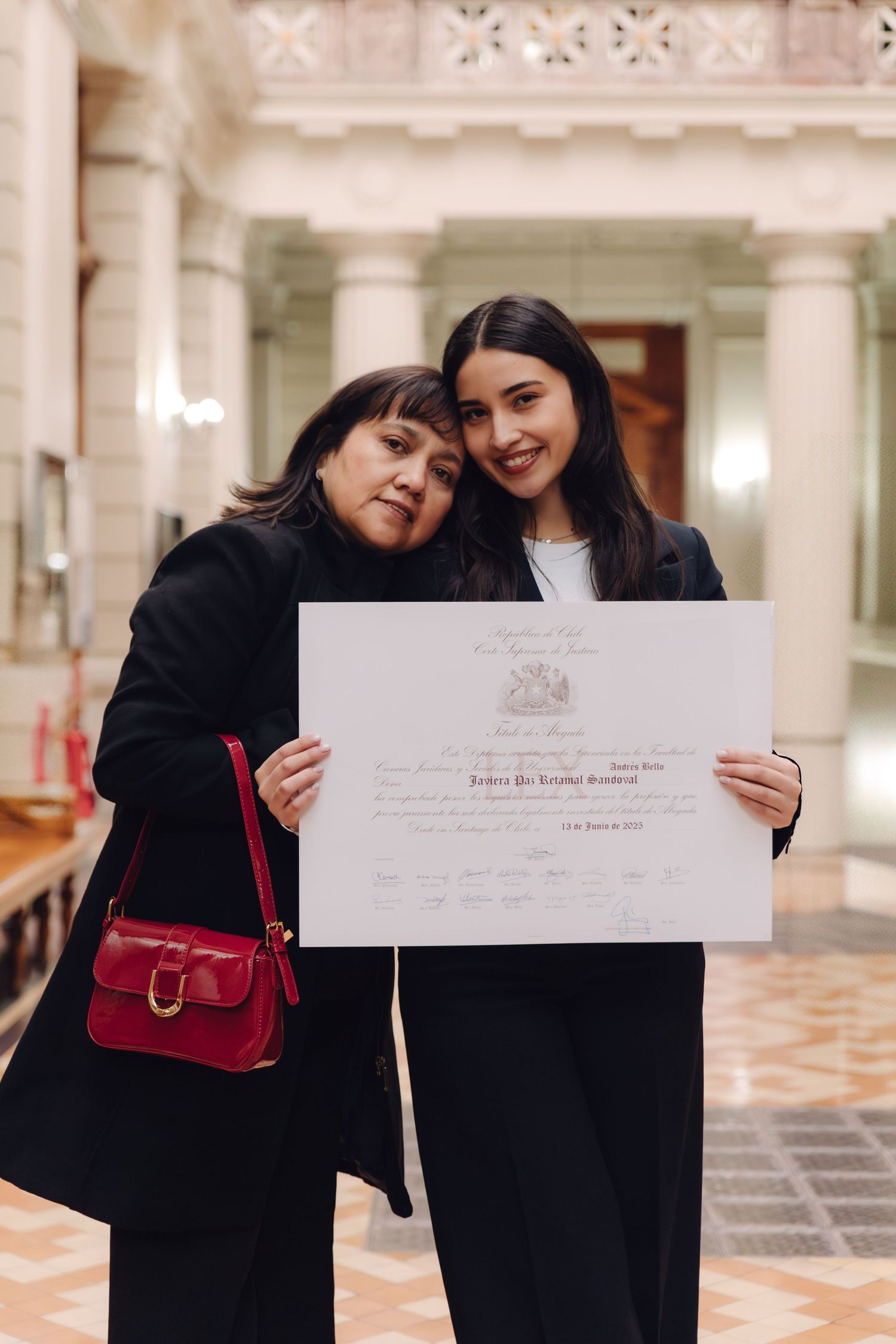 Mother and daughter share proud moment holding graduation certificate together.