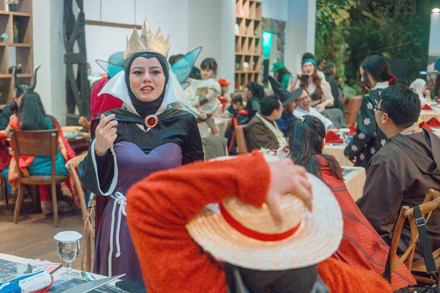 Evil Queen cosplayer interacts with guests at a themed costume party event.