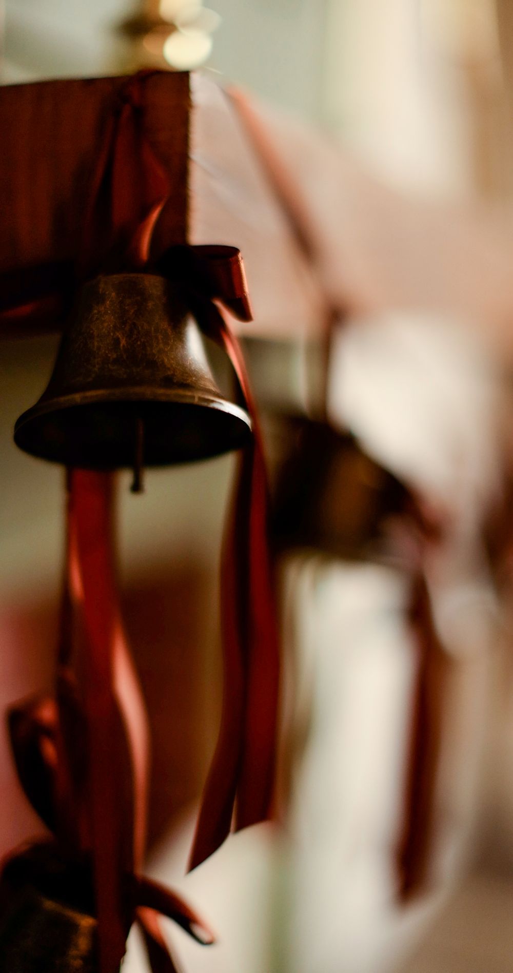 Vintage bronze bell with red satin ribbons hanging as a classic Christmas holiday decoration.