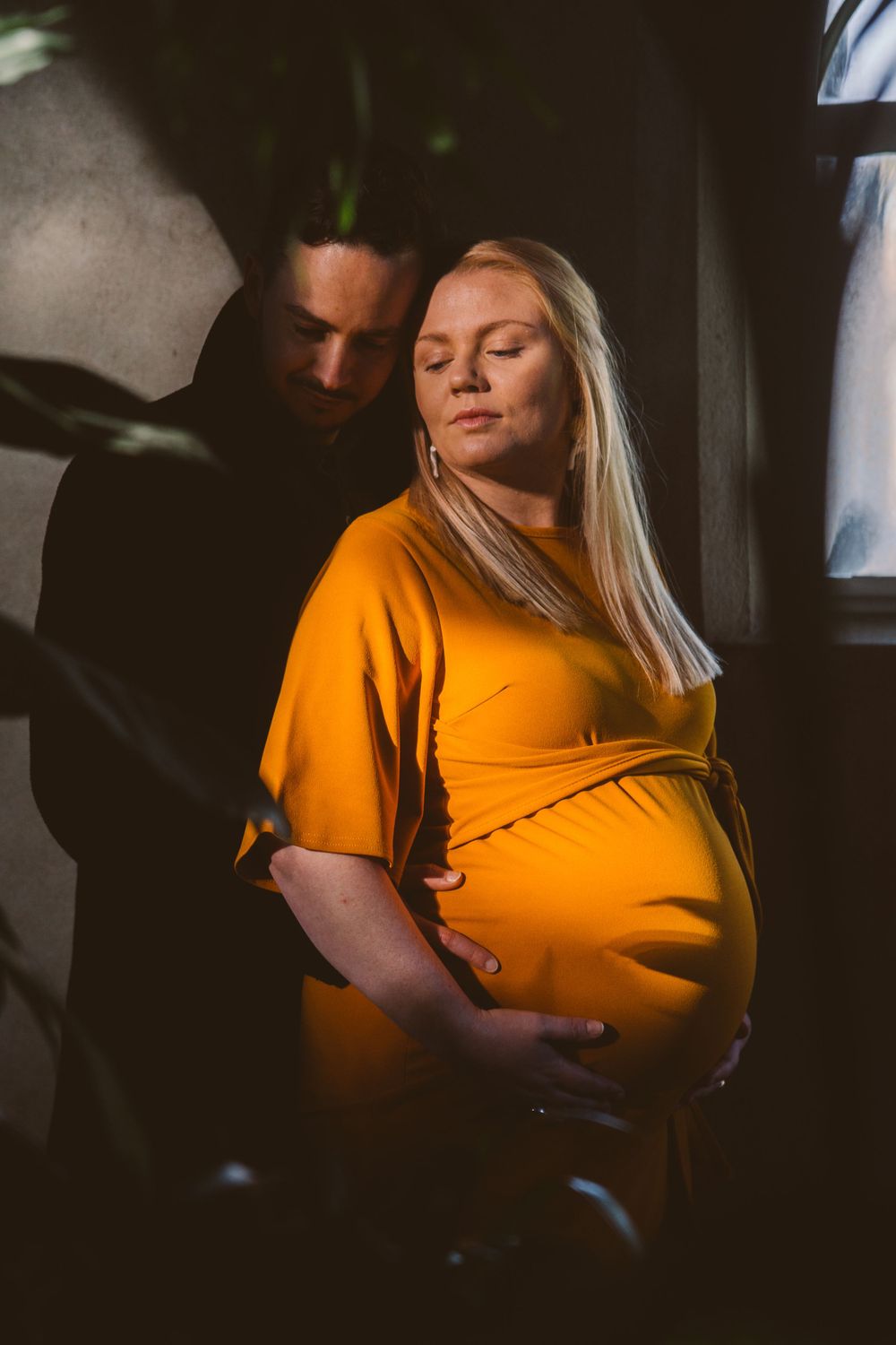 Pregnant couple standing having a quiet moment with strong light