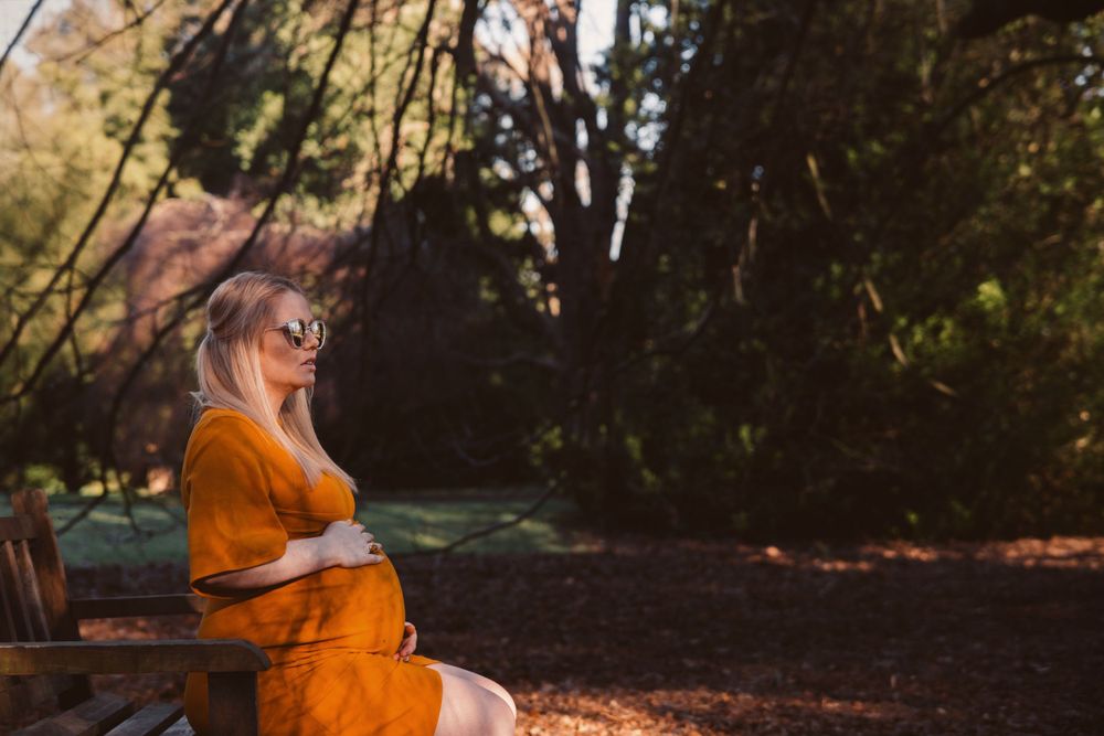 pregnant lady sitting on a park bench in Christchurch