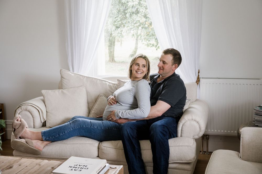 Couple sitting on a couch at home on the West Coast for a maternity photo