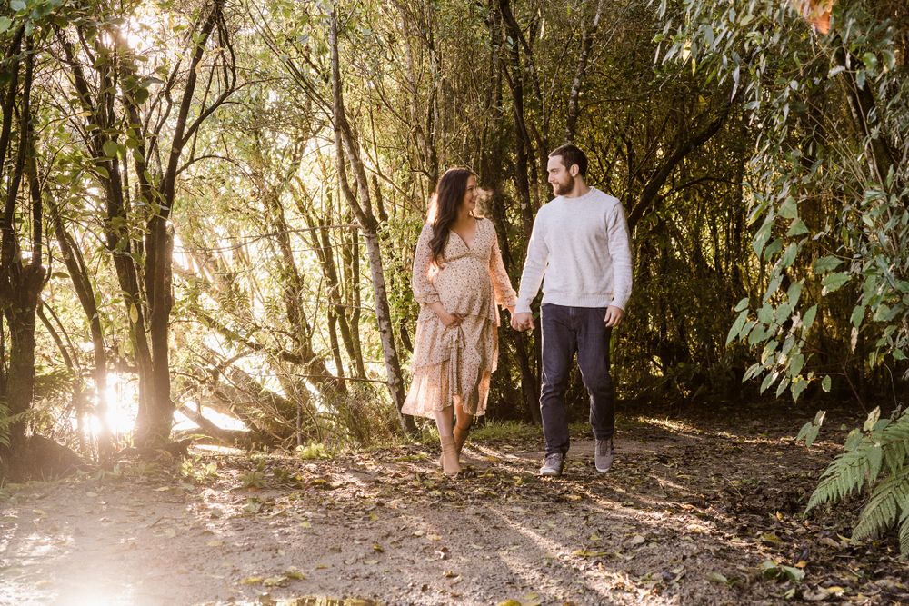 pregnant lady with partner walking amongst trees on the West Coast of New Zealand