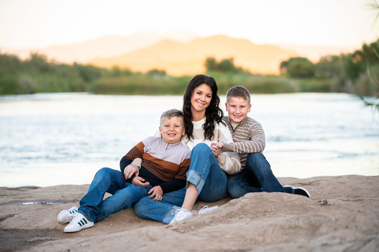 Mother and two sons smiling together in front of the Salt River during their Arizona family vacation photography session.