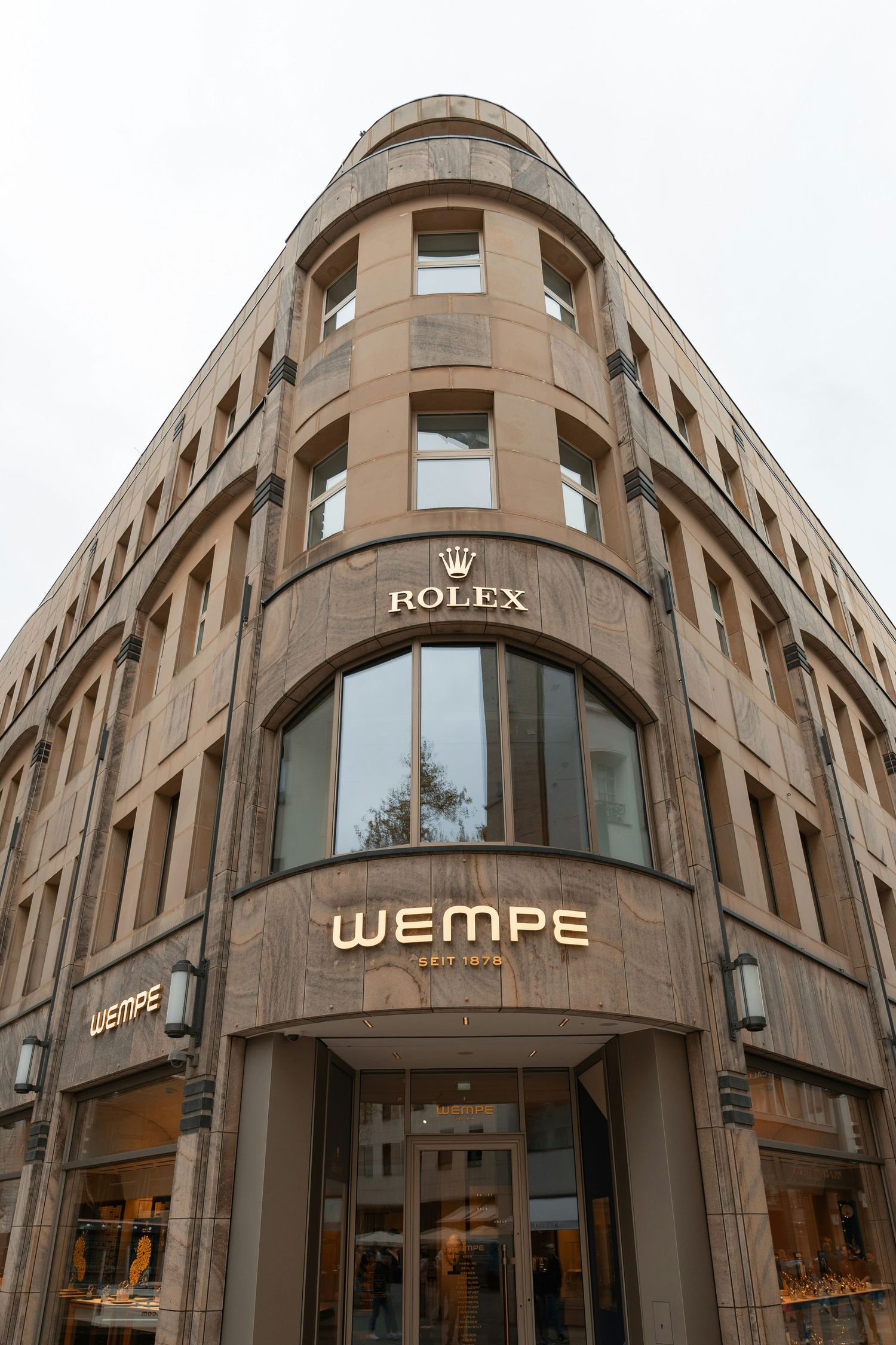 Exterior view of Wempe luxury jewelry store with Rolex signage on an elegant stone building facade.