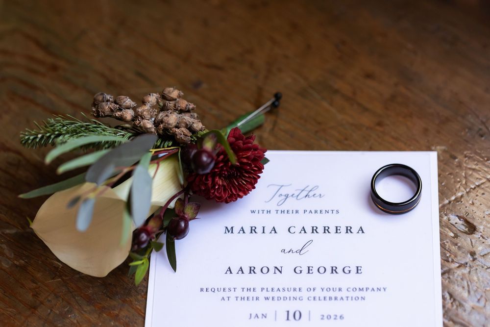 Wedding invitation for Maria Carrera and Aaron George on Jan 10, 2026, with floral boutonniere and gold ring.