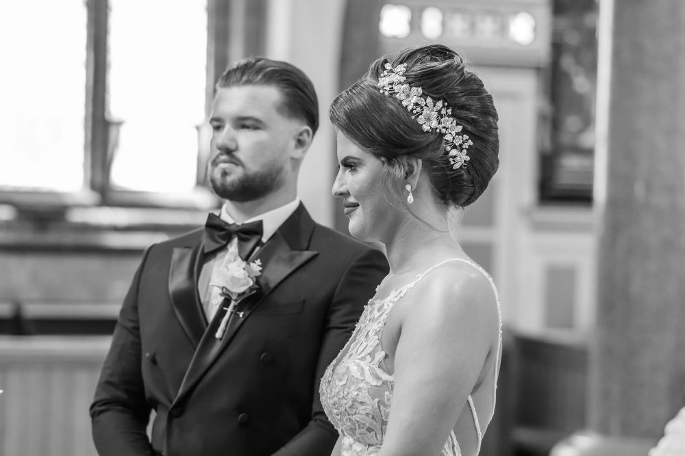 Black and white photo of a bride and groom standing at the altar during their wedding ceremony.