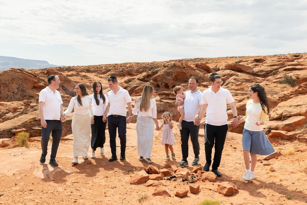 Large family group posing together in a red rock desert landscape under a cloudy sky.