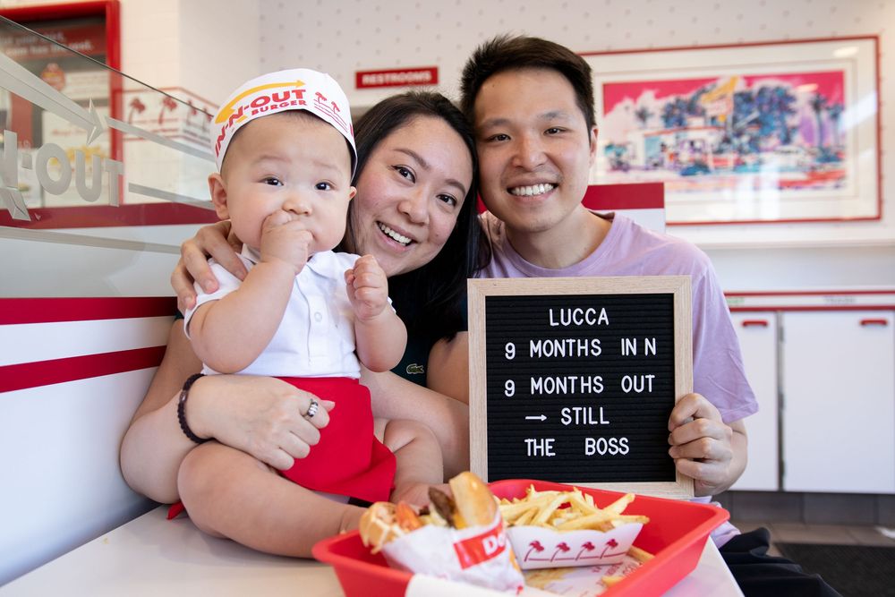 Family celebrating baby Lucca's 9-month milestone at In-N-Out Burger with a letter board sign.