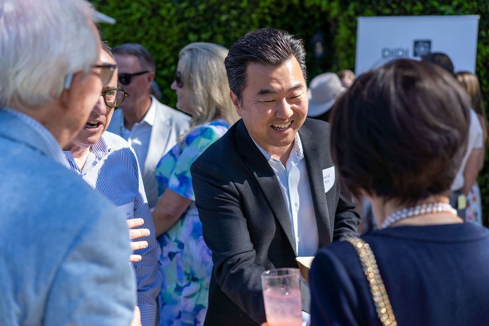 People socializing outdoors at an elegant garden party event on a sunny day.