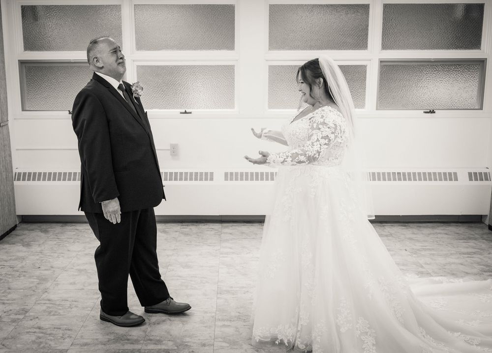 Black and white wedding photo of bride in lace gown and groom during first look ceremony indoors.
