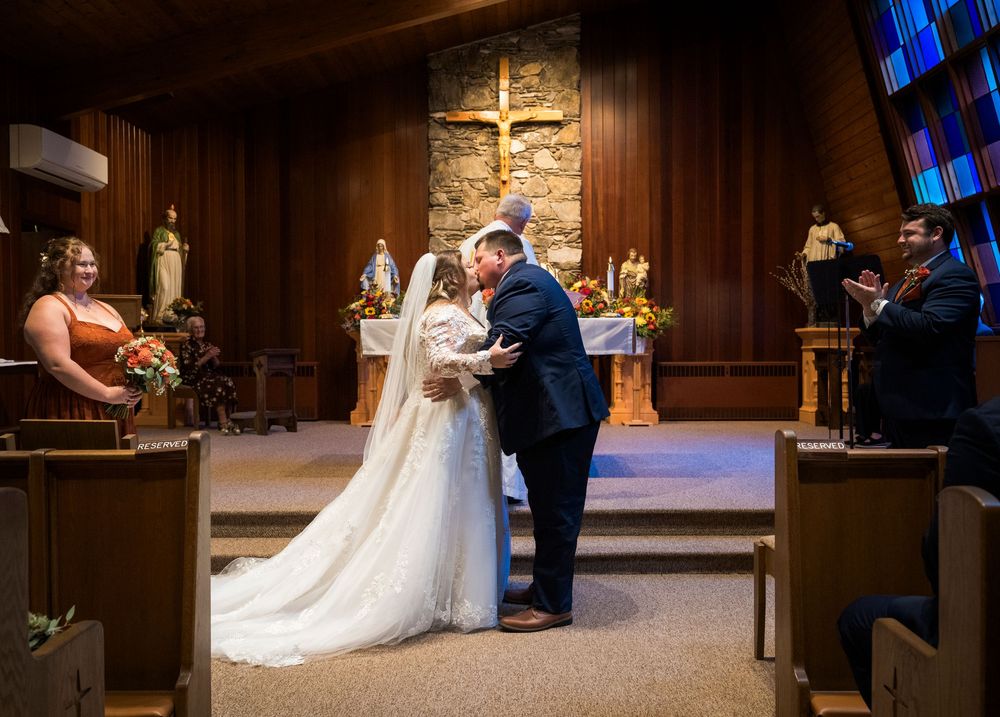 Newlyweds share first kiss at Catholic church altar after wedding ceremony.
