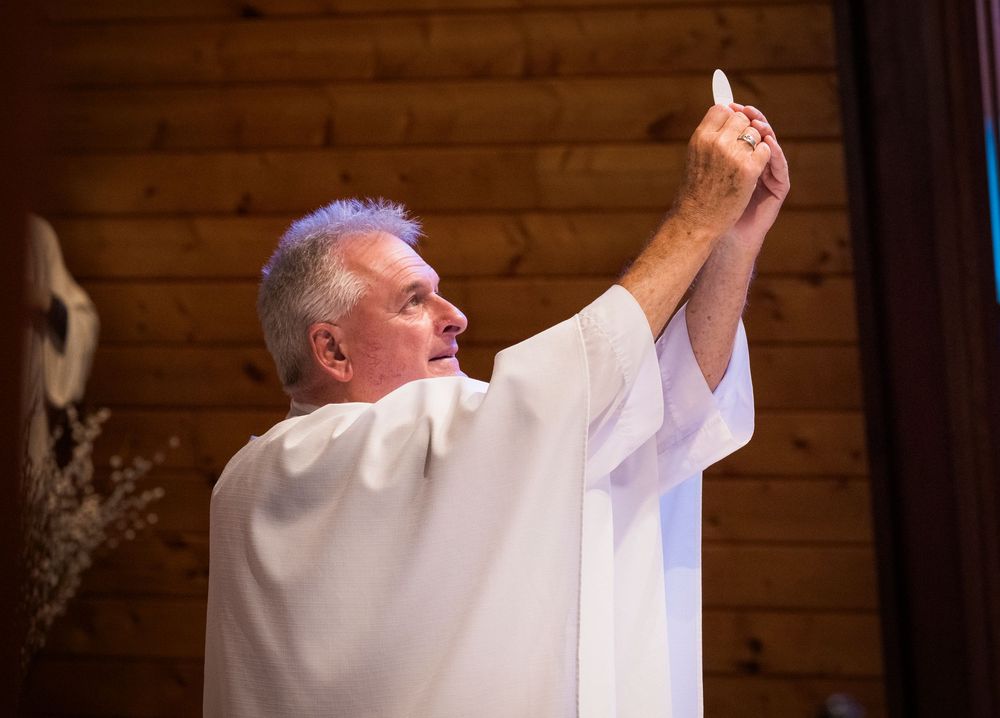 Catholic priest elevates communion host during wedding Mass ceremony.