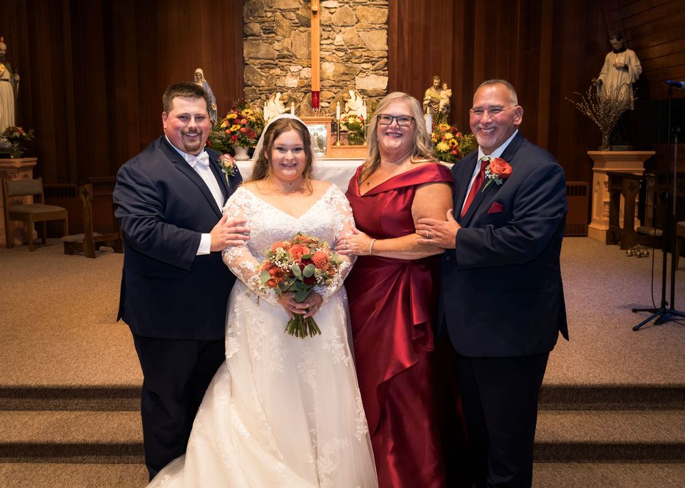 Bride and groom pose with family members in Catholic church after wedding.