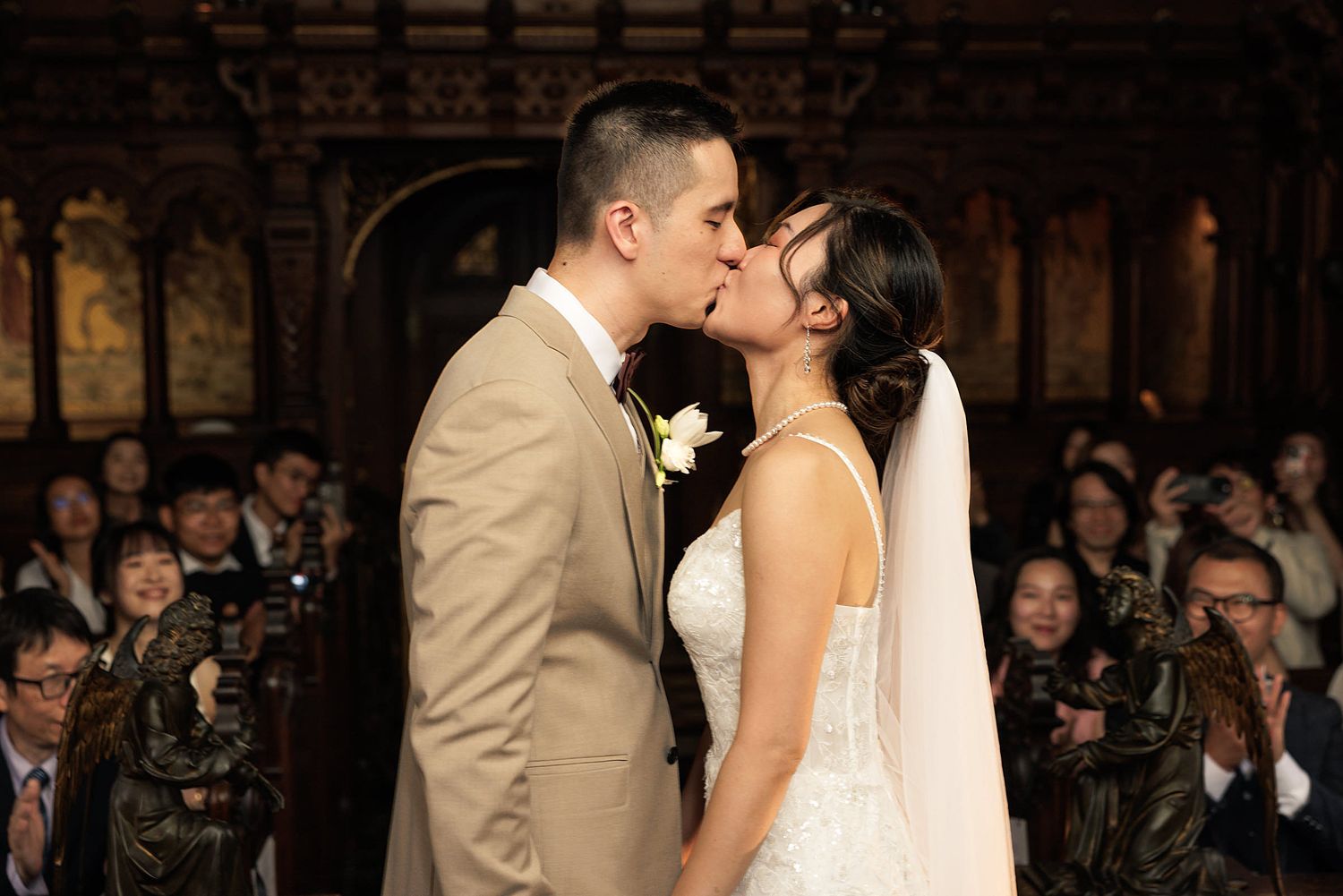A bride and groom walk hand-in-hand through an elegant stone courtyard of a historic building.