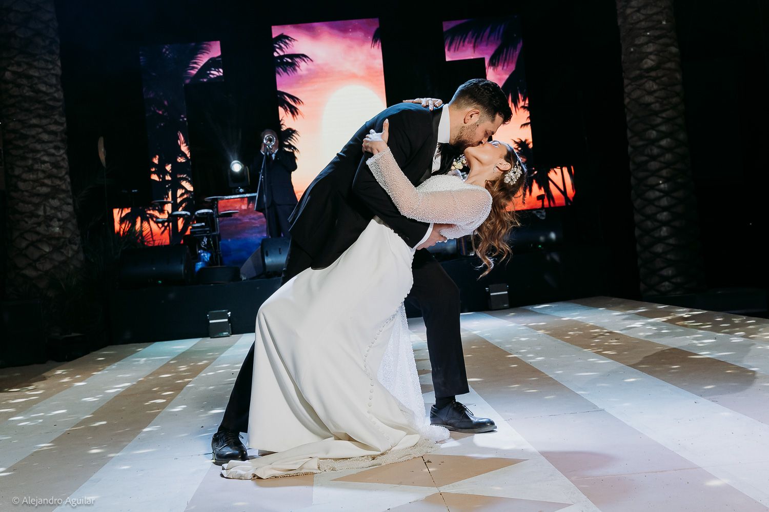 Bride and groom share a romantic dip kiss on the dance floor during their first dance at a wedding reception.