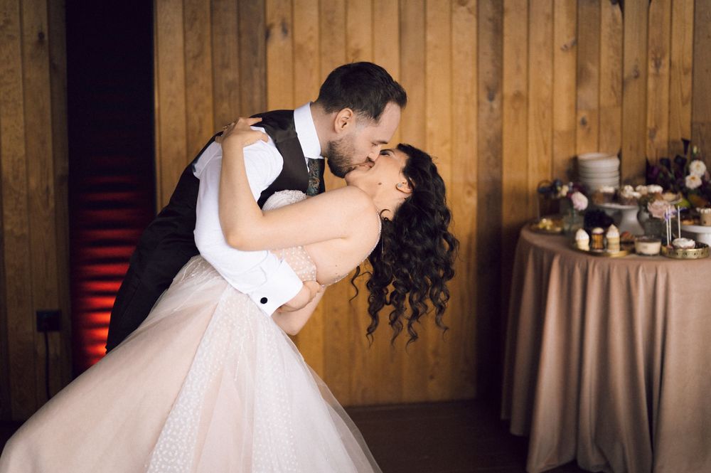 Bride and groom share a romantic dip kiss on the dance floor at their wedding reception.