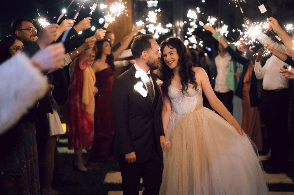 Bride and groom share a romantic moment during a sparkler send-off at their elegant evening wedding reception.