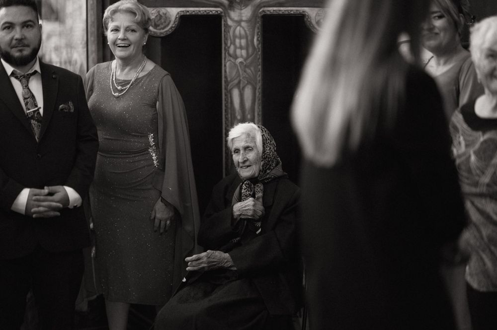 Black and white photo of elderly woman seated, smiling woman standing beside her, formal event setting.