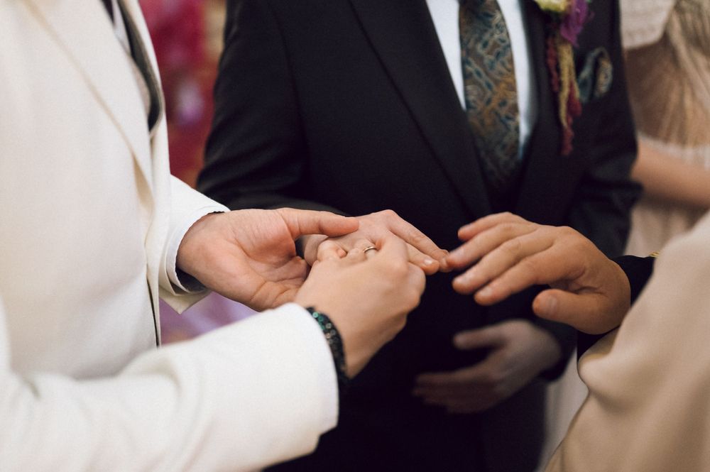Close-up of groom placing wedding ring on bride's finger during wedding ceremony.